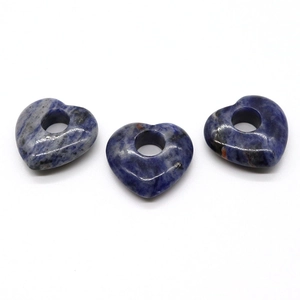 Gros plan de pierres de sodalite polies en forme de cœur avec trou central pour bijoux DIY