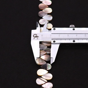 Makro-Detail von schwarzen Muschelperlen in Tropfenform mit 10mm Maßstabsmessung