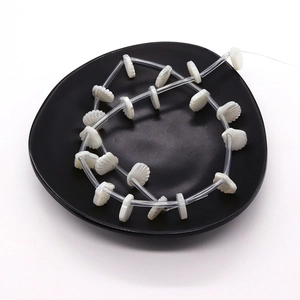 Perles de nacre blanches en forme d'éventail pour bijoux DIY sur une assiette noire