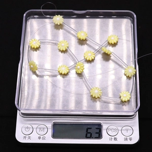 Weight measurement of yellow daisy shell beads on a digital scale for DIY jewelry