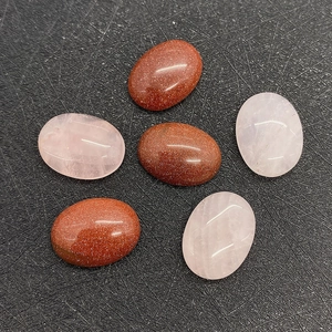 Detailed macro view of 12x16mm oval polished goldstone and rose quartz cabochons