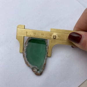 Détail d'un pendentif en agate verte naturelle mesuré avec un pied à coulisse