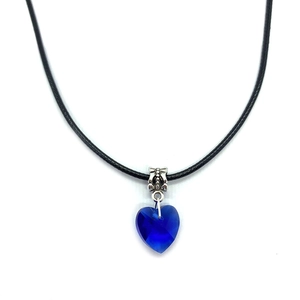 Macro detail of deep blue faceted crystal heart pendant with silver textured bail