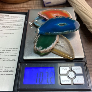 Vue détaillée de quatre pendentifs en tranches d'agate colorées sur une balance