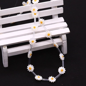 Detail of white daisy shell flower beads with yellow center on a display stand
