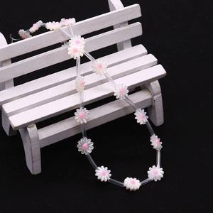 Macro detail of white daisy flower beads with pink centers on a necklace string