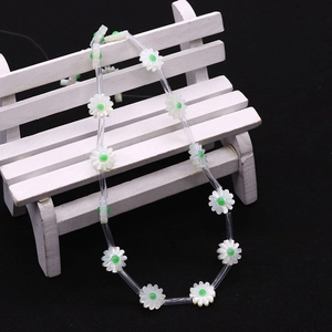 Detail of flower beads made of natural shell with green centers on a miniature bench