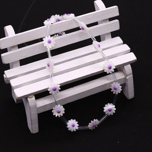 Detail of daisy shell beads with purple centers on a miniature white park bench model