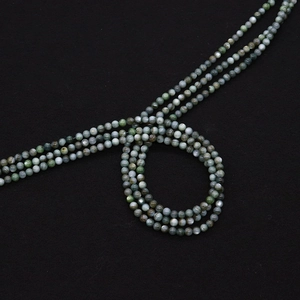 Macro-opname van donkergroene schelpkralen met kattenoogeffect voor DIY-sieraden