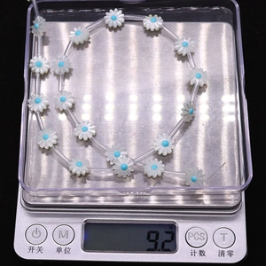 Close-up of shell daisy beads weighed on a digital scale for DIY jewelry making