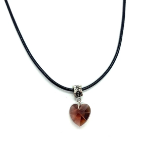 Macro detail of a heart-shaped amber crystal faceted pendant with a silver carved bail