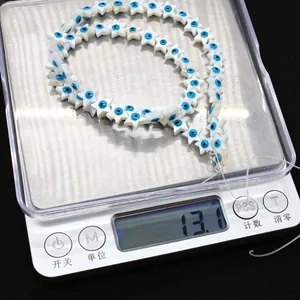 Nahaufnahme von Sternperlen aus Muschel mit blauem Auge-Motiv auf einer Waage
