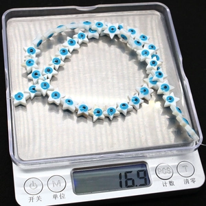 Macro shot showing 16.9g weight of star-shaped evil eye beads on digital scale