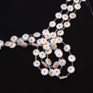 Macro shot of daisy-shaped white shell beads with orange centers for DIY jewelry making