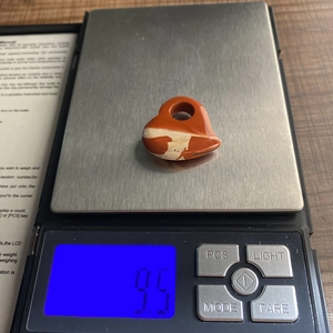 Macro-opname van 9,5g gewicht van hartvormige rode jaspis hanger op een digitale weegschaal