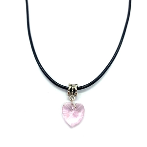 Close-up of pink faceted heart crystal pendant with silver embossed bail on black cord