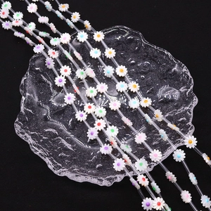 Daisy shaped seashell beads with colorful enamel centers on elegant glass display tray
