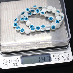 Flat round evil eye shell beads weighing 14.7 grams on a digital scale for DIY jewelry