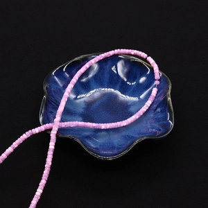Dettaglio macro di perle di conchiglia rosa 2x4mm in una ciotola di ceramica a fiore