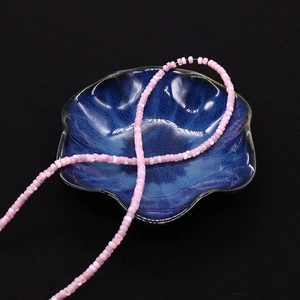 Vista macro di perle distanziatrici in conchiglia rosa su un vassoio di ceramica