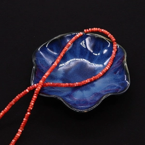 Dettaglio macro di perline di conchiglia rossa disposte su una ciotola di ceramica blu