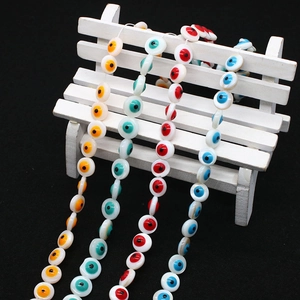 Detail of 9mm natural shell evil eye beads in yellow, green, red and blue on a mini bench