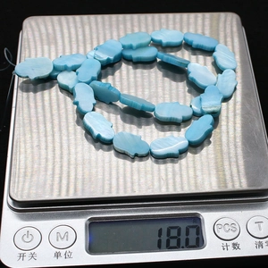 Detailansicht von 18,0g blauen Hamsa-Perlen mit Wellenstruktur auf einer Waage