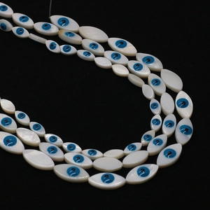 Macro detail of marquise natural shell beads with blue evil eye patterns for DIY jewelry