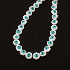 Macro detail of 9mm natural shell beads featuring turquoise evil eye charms for DIY jewelry