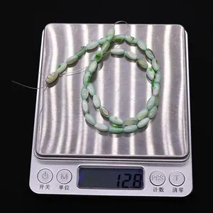 Macro-opname van lichtgroene ovale schelpkralen van 12,8 g op een digitale weegschaal