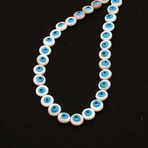 Detailed view of 9mm natural freshwater shell evil eye beads on a dark surface