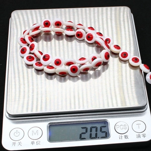 Macro shot of 9mm Evil Eye shell beads showing a total weight of 20.5 grams on a digital scale