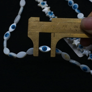 Mesure détaillée de perles en nacre avec motif œil grec à l'aide d'un pied à coulisse