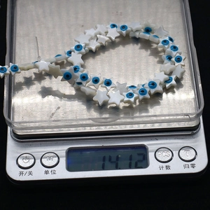 Perles en nacre en forme d'étoile avec motif œil bleu sur une balance de précision