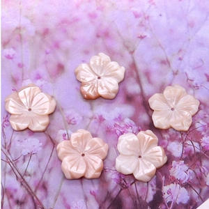 Detailed macro view of five pink carved mother of pearl cherry blossom flower beads