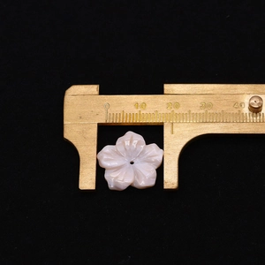 Macro shot of 20mm pink freshwater shell flower pendant measured with brass caliper