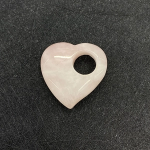 Gros plan sur un cristal de quartz rose poli en forme de cœur avec texture naturelle