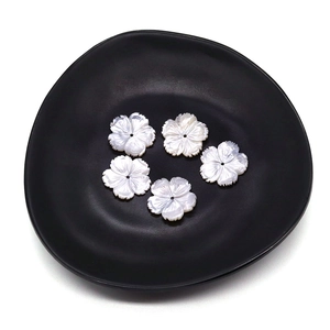 Perle a fiore in conchiglia bianca scolpita 20mm con riflessi perlati su piatto nero