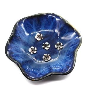 Perles de fleurs en nacre noire dans un plat en céramique bleue pour la création de bijoux