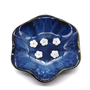 Fünfblättrige weiße Muschelperlen für Schmuck in einer blauen Keramikschale