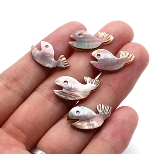 Hand hält 5 walförmige Perlmuttperlen aus Naturmuscheln mit schillerndem Glanz