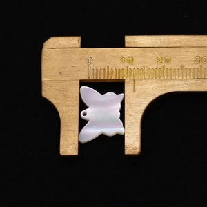 Makroansicht eines 12mm Schmetterling-Perlmuttanhängers auf einem Messschieber
