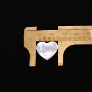 Macro shot of a 20mm heart-shaped white mother of pearl shell bead with rainbow luster