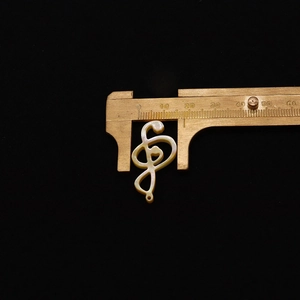 Vue détaillée d'un pendentif clé de sol de 30mm en nacre naturelle avec reflets irisés