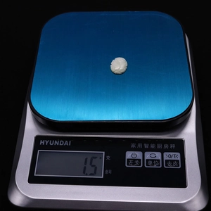 Detailed macro shot of white shell cabochon on a digital scale weighing 1.5 grams