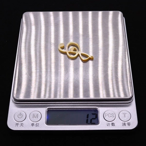 Macro d'un pendentif note de musique en coquillage jaune de 1,2g sur une balance