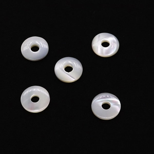 Vue macro de cinq perles en nacre naturelle blanche avec reflets sur fond noir profond