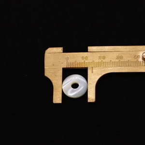 Détail montrant la mesure d'une perle de nacre blanche de 15mm pour pendentif rond