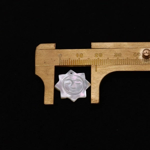 Vue détaillée d'une breloque soleil en nacre sculptée de 20 mm aux reflets irisés