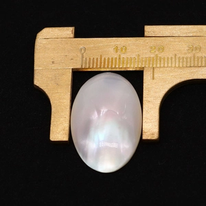 Macro shot of oval white mother of pearl cabochon with iridescent sheen measuring 18mm